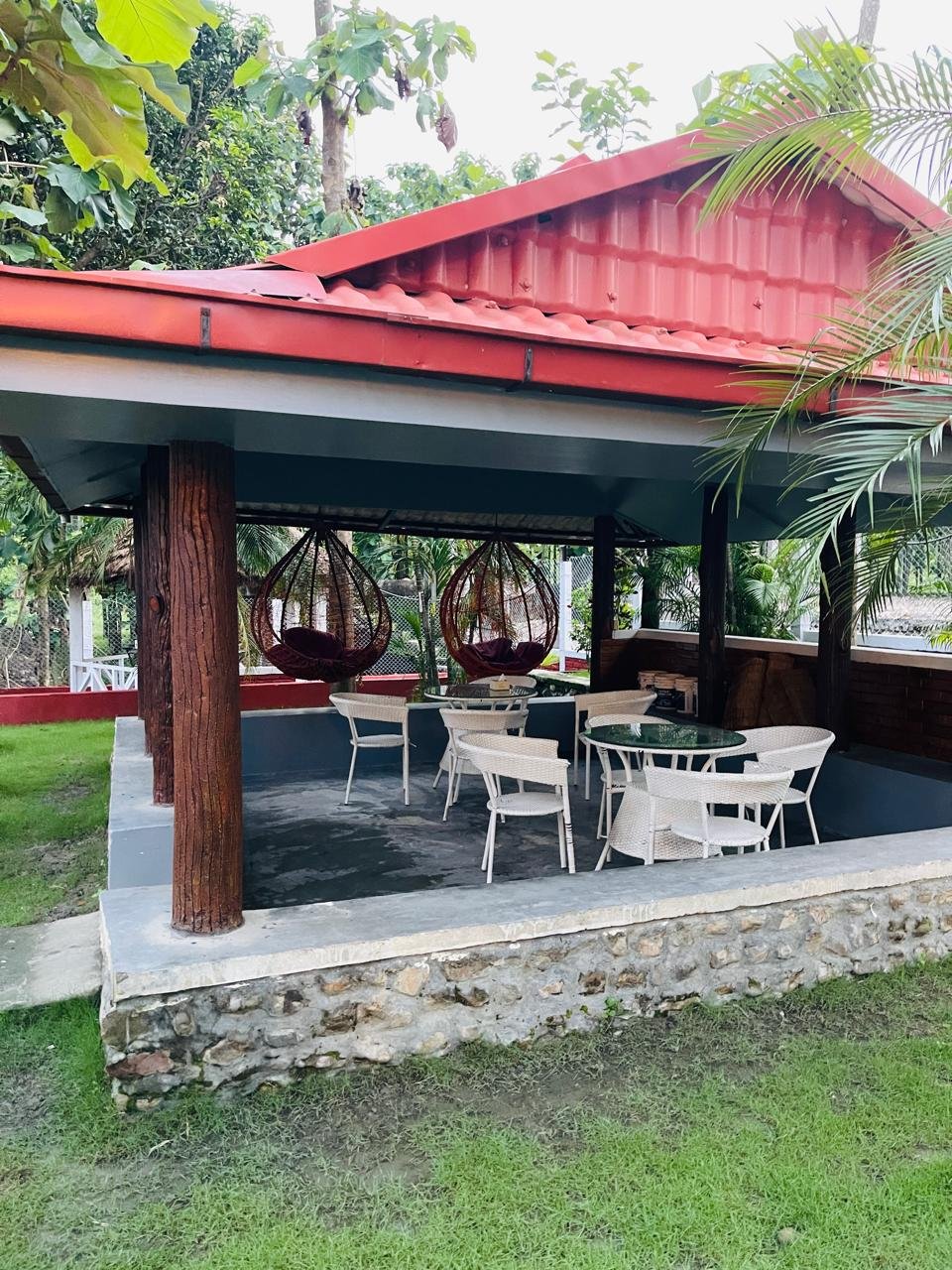 Shaded garden gazebo with hanging chairs at Shanti Sudha Resort